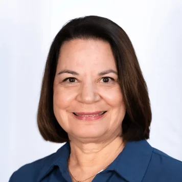 A woman with short hair dressed in a blue shirt, posing confidently for the photograph.